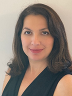 A headshot of Dr Kimia Ziahosseini who has dark shoulder-length hair and is smiling towards the camera.