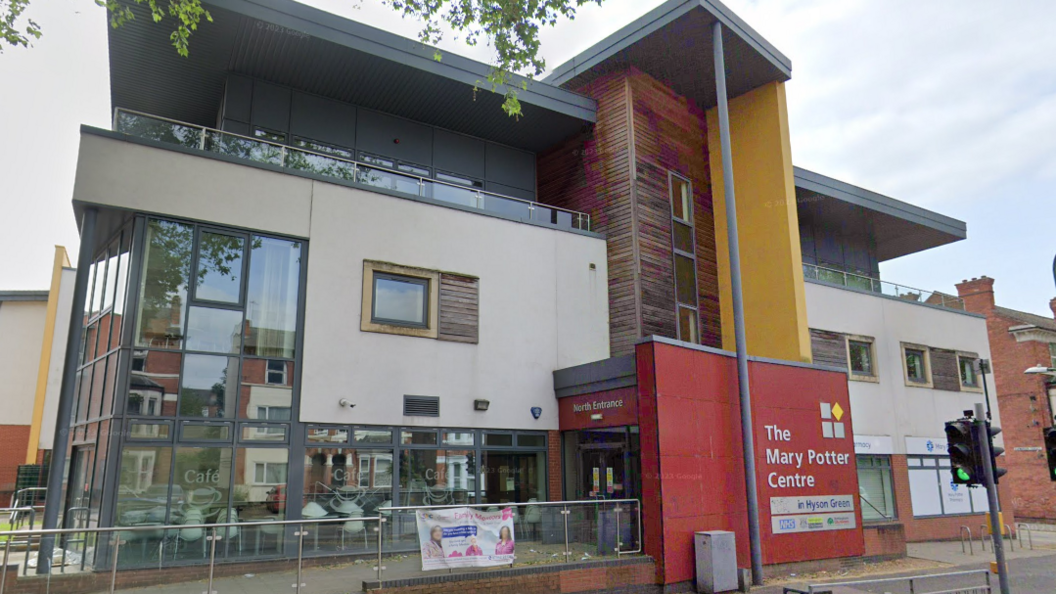Mary potter centre is a big colourful building a red entrance with a yellow and wood panelled taller section.