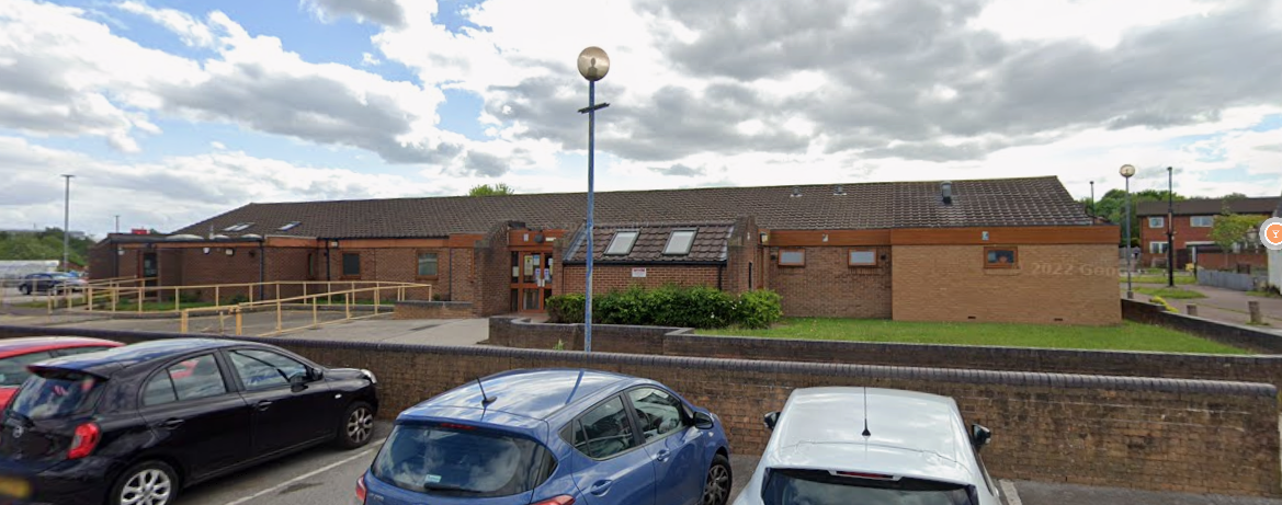 Oak tree lane health centre large flat brown brick building with parking. 