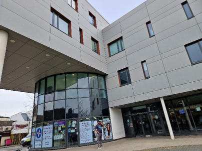 Outside of Loxford Polyclinic. A white building with a glass round entrance.