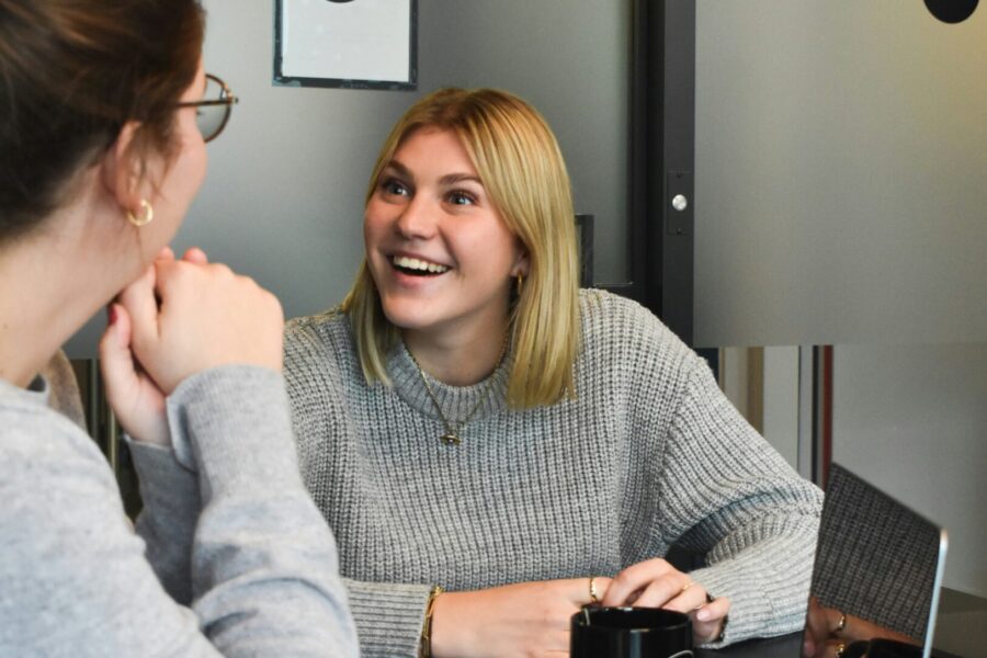 two woman sat at desk with open laptop on table