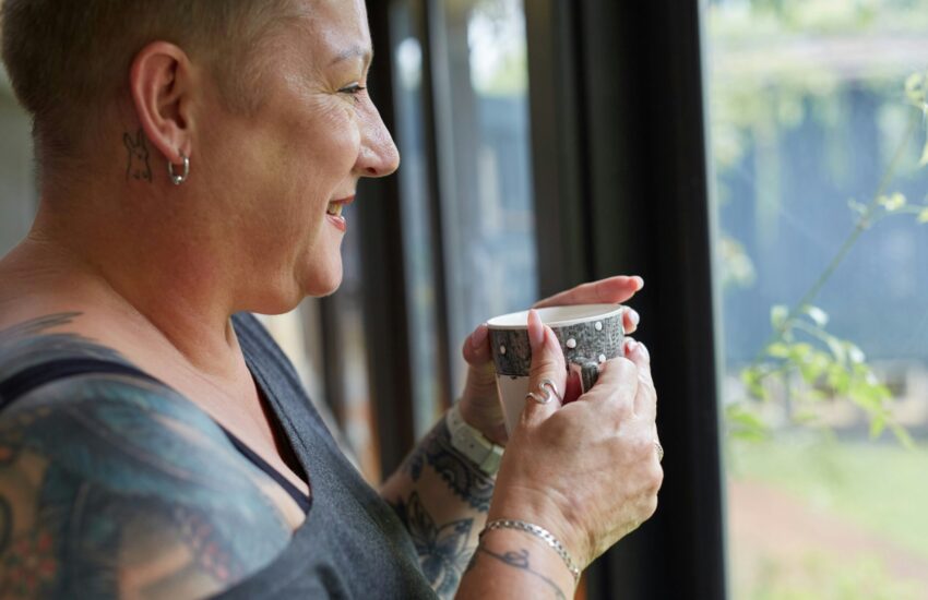 Lady looking out of window and drinking tea
