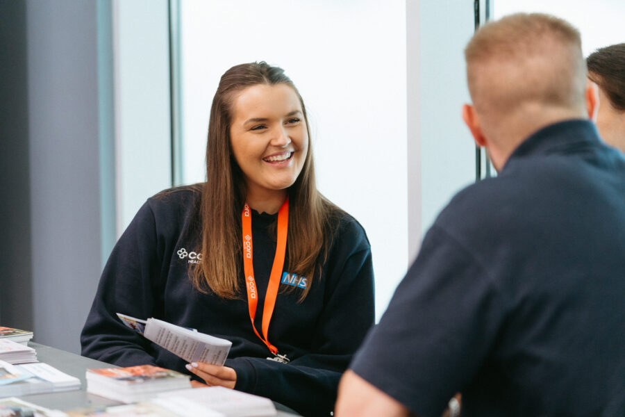 A female Cora team member sitting across from an event attendee. She's smiling and holding a notepad.
