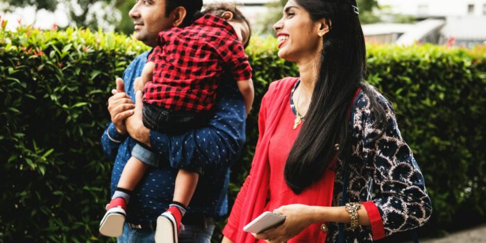 A smiling couple with a small child carried by the father.