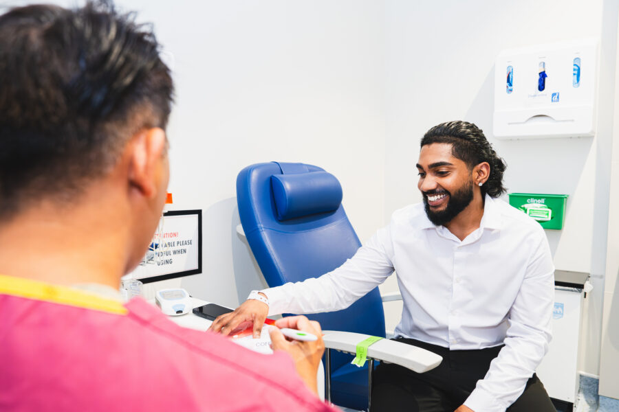 Man sat in a clinic setting speaking to a clinician smiling.