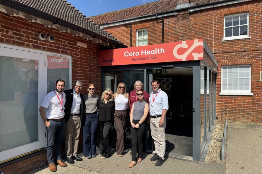 Group of people standing infront of the cora branded front door of Norwich clinic.