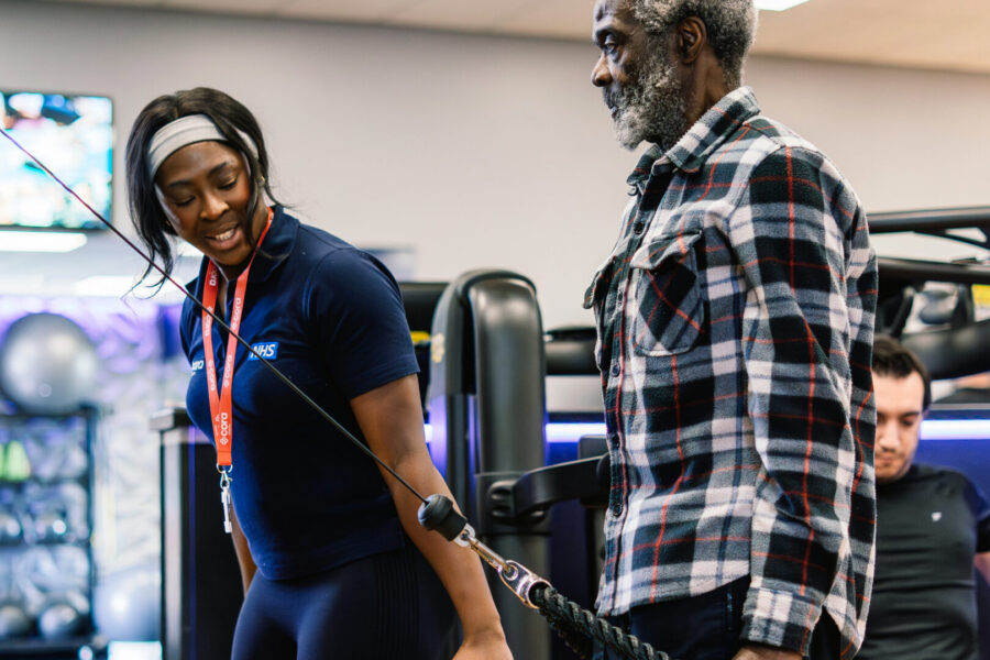 Female physiotherapist showing man in gym setting how to use the equipment